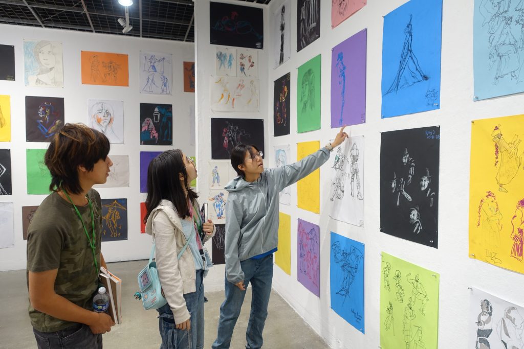 Students looking at gallery wall and life drawings.